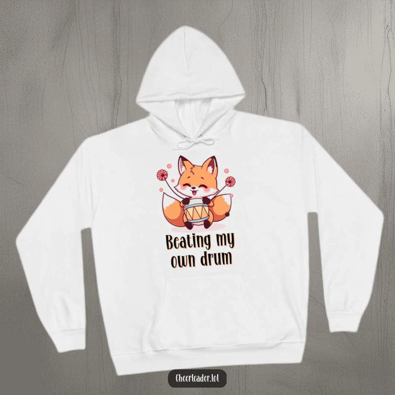 Funny fox playing a tiny drum with pom-poms, depicted on a warm and comfortable hoodie.