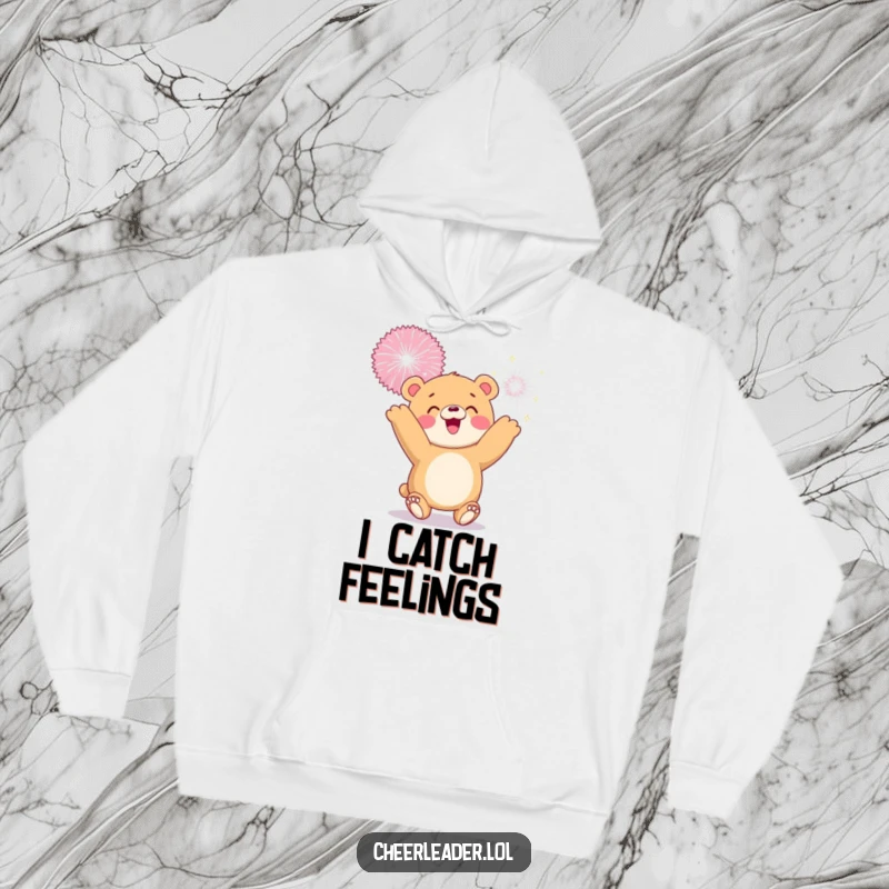 Funny hoodie illustration of a smiling bear cub tossing a giant sparkly pom-pom, embodying playful excitement.